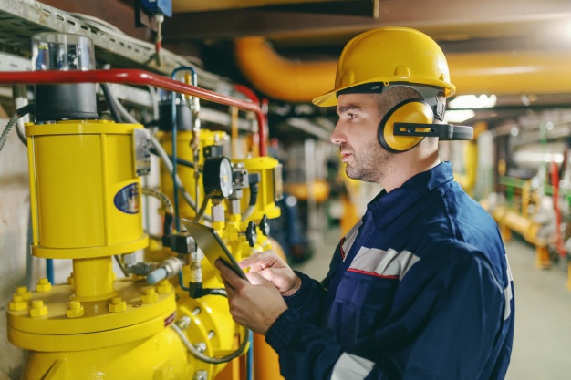 perfil-de-trabalhador-trabalhador-com-capacete-antifones-e-em-traje-de-protecao-verificando-a-pressao-do-ar-nas-caldeiras-em-pe-na-planta-da-industria-pesada_232070-2451 O que são treinamentos obrigatórios de Saúde e Segurança do Trabalho (SST)?